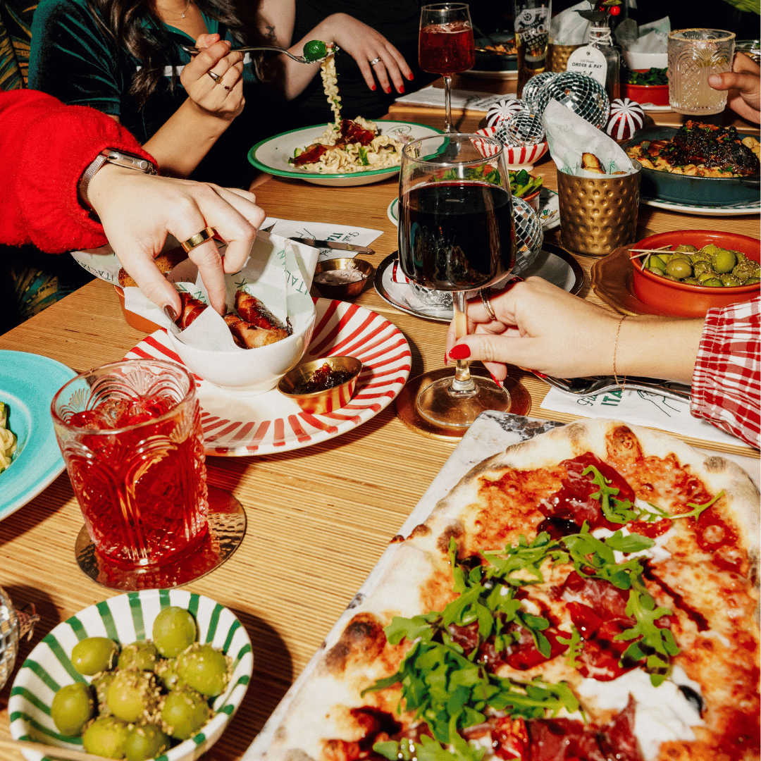 A festive looking table at a restaurant, filled with food such as pizza and pasta with disco balls decorating the table. 