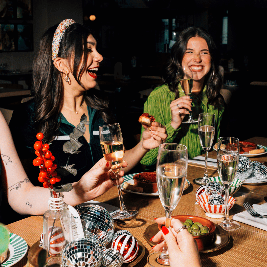 A group of friends enjoying a Christmas lunch or dinner cheersing with their prosecco glasses. 