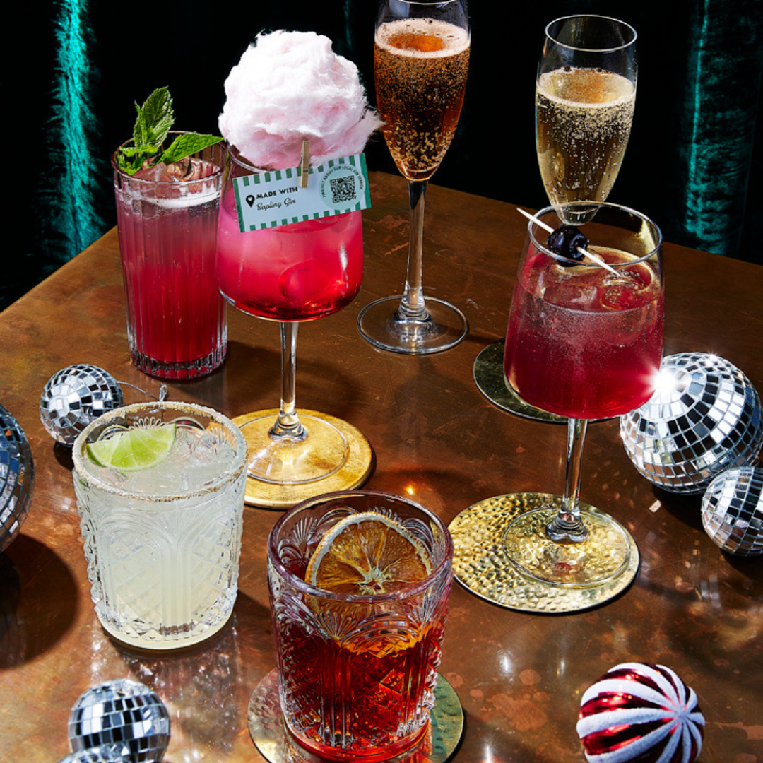 A collection of Christmas and festive drinks on a table decorated with disco balls and baubles. 